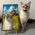 Custom pet portrait: real cat beside its personalized cat painting featuring a windmill, ideal pet wall art gift.